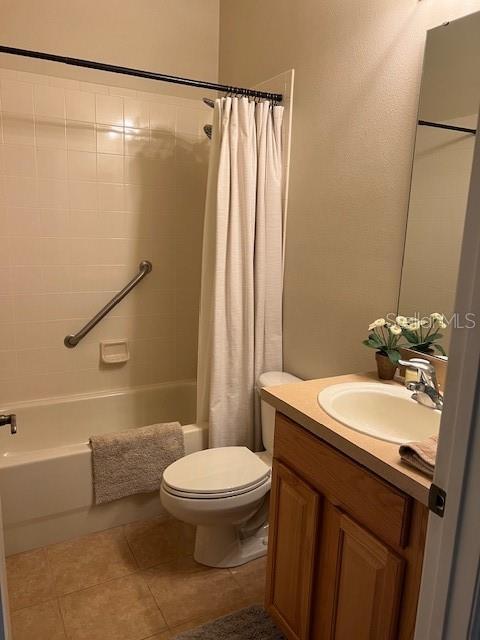 bathroom featuring tile patterned flooring, shower / tub combo with curtain, toilet, and vanity