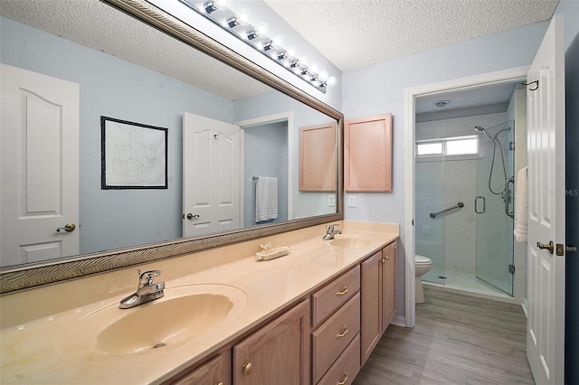 full bathroom featuring a textured ceiling, a sink, toilet, and a stall shower