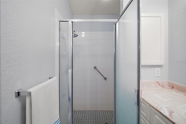 bathroom featuring vanity, a textured wall, a stall shower, and a textured ceiling
