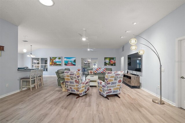 living room featuring vaulted ceiling, a textured ceiling, light wood-type flooring, baseboards, and ceiling fan