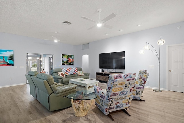 living room with a ceiling fan, visible vents, a textured ceiling, and wood finished floors