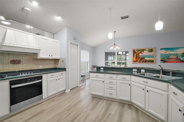 kitchen featuring a sink, white cabinetry, custom range hood, stainless steel appliances, and visible vents