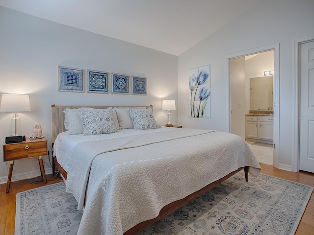 1829 Foxwood Ln, The Villages, FL 32162 - bedroom with connected bathroom, lofted ceiling, baseboards, and light wood-style flooring