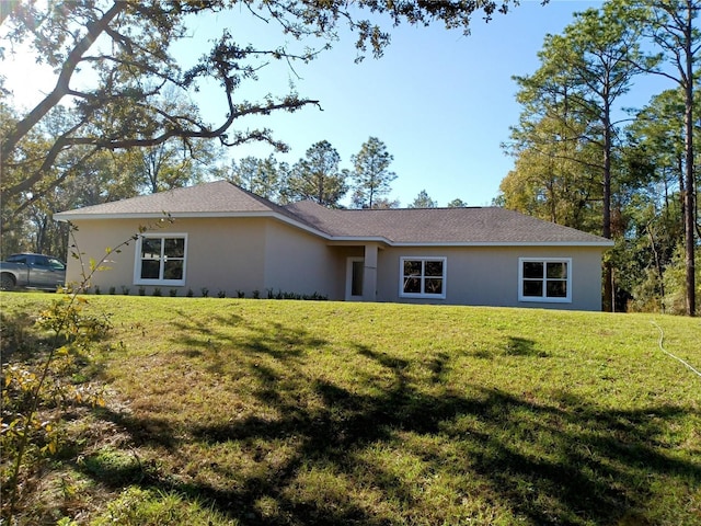 rear view of property with stucco siding and a lawn