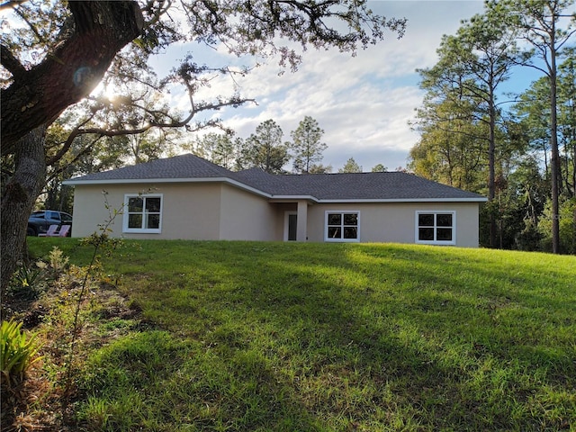 back of house featuring stucco siding and a yard