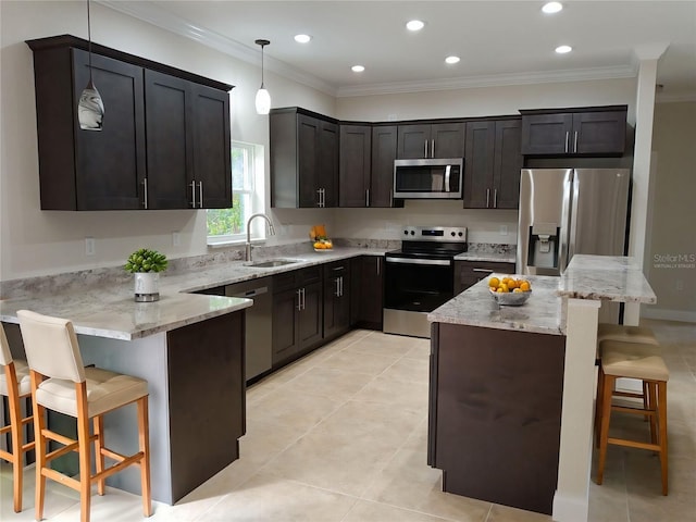 kitchen with light stone countertops, appliances with stainless steel finishes, a breakfast bar, and a sink