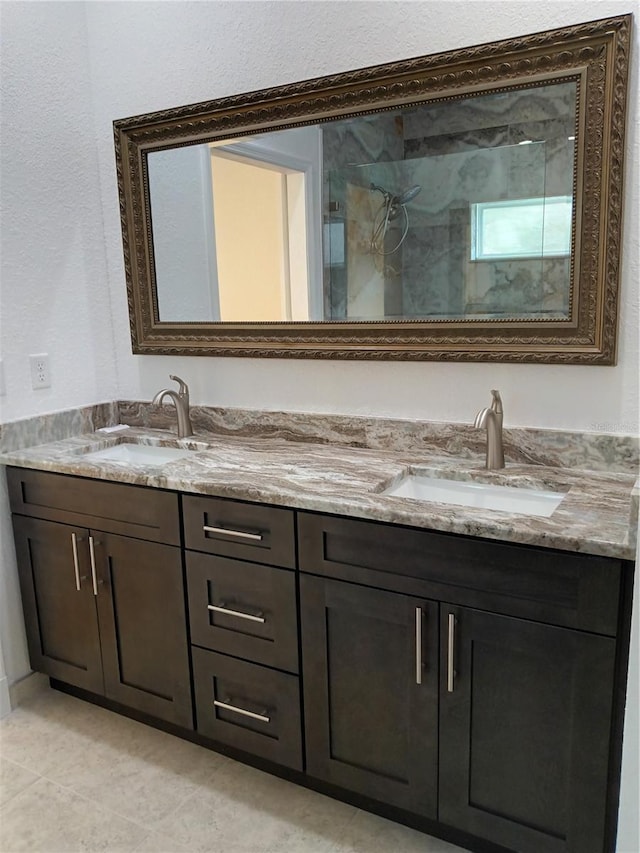 bathroom featuring double vanity, a marble finish shower, and a sink