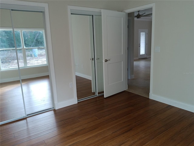 unfurnished bedroom featuring baseboards, two closets, and dark wood finished floors