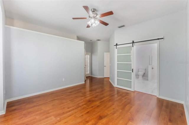 6200 Topsail Rd, Lady Lake, FL 32159 - unfurnished bedroom with visible vents, light wood-style flooring, baseboards, and a barn door