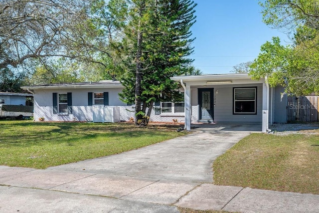 single story home featuring a carport, driveway, a front lawn, brick siding, and fence