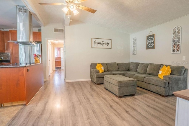 living room featuring light wood-style flooring, ceiling fan, lofted ceiling, and visible vents