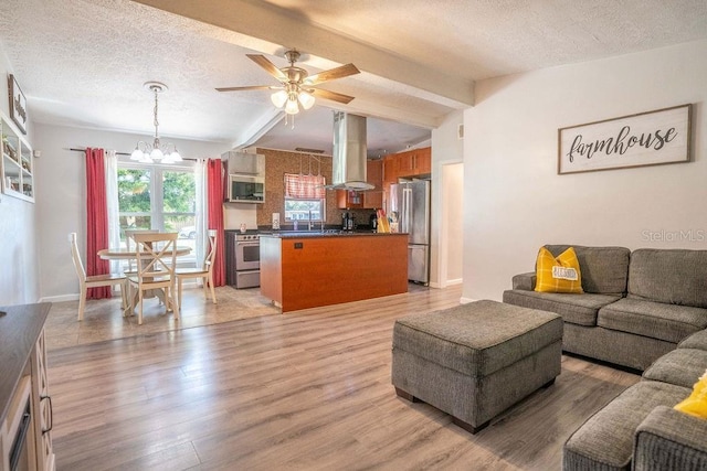 living area featuring light wood-style flooring, a textured ceiling, ceiling fan with notable chandelier, and vaulted ceiling with beams