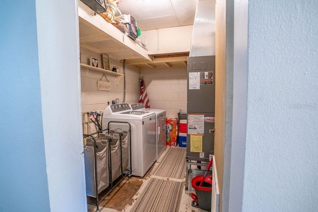 clothes washing area featuring washing machine and dryer, laundry area, and concrete block wall