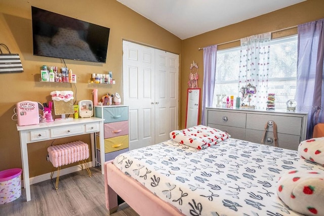 bedroom featuring baseboards, a closet, wood finished floors, and lofted ceiling