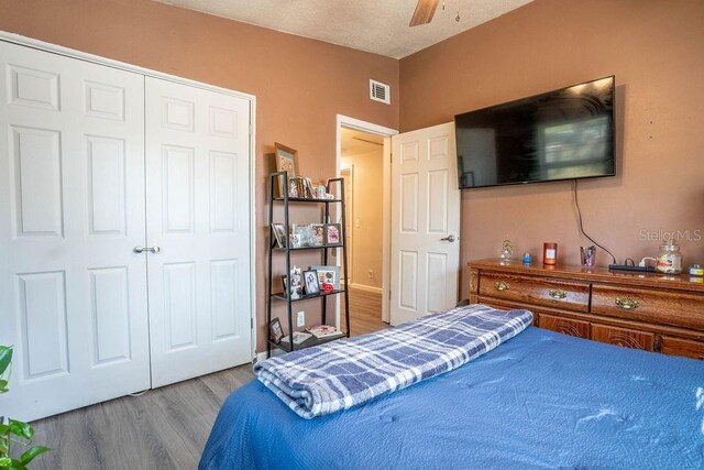 bedroom with visible vents, ceiling fan, a closet, and wood finished floors
