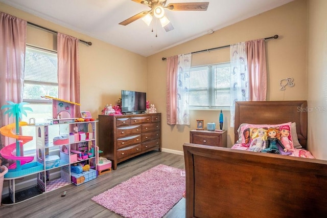bedroom with baseboards, ceiling fan, wood finished floors, and lofted ceiling