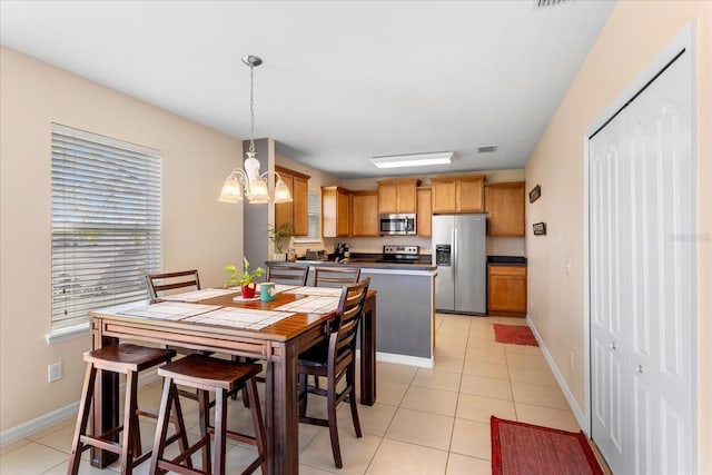 dining space with a chandelier, light tile patterned floors, and baseboards