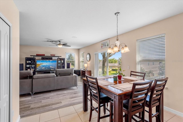 dining area featuring ceiling fan with notable chandelier, baseboards, and light tile patterned flooring