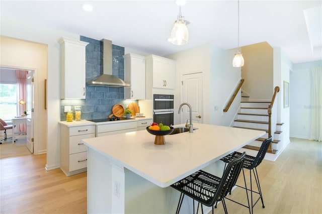 981 Fiesta Key Cir, Lady Lake, FL 32159 - kitchen with light wood-type flooring, black appliances, a sink, tasteful backsplash, and wall chimney range hood