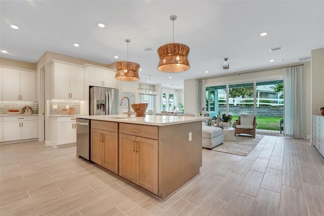 981 Fiesta Key Cir, Lady Lake, FL 32159 - kitchen featuring appliances with stainless steel finishes, open floor plan, a sink, light countertops, and backsplash