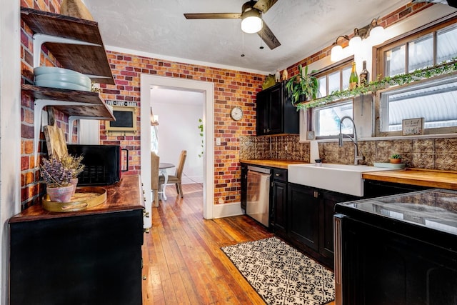 kitchen with dark cabinets, a sink, dishwasher, and wooden counters