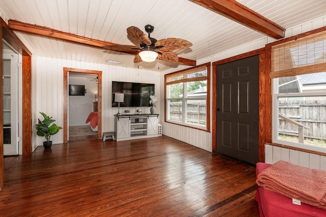 living room featuring wood-type flooring, beam ceiling, wooden walls, wood ceiling, and a ceiling fan