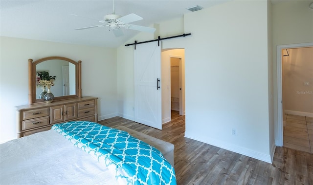 1046 Ridgeland Path, The Villages, FL 32162 - bedroom featuring vaulted ceiling, baseboards, a barn door, visible vents, and wood finished floors