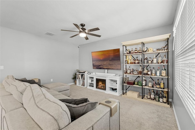 2636 Neverland Dr, New Smyrna Beach, FL 32168 - living area featuring visible vents, a warm lit fireplace, carpet, baseboards, and ceiling fan
