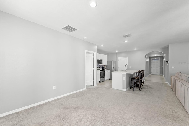 2636 Neverland Dr, New Smyrna Beach, FL 32168 - kitchen with visible vents, a kitchen bar, a sink, appliances with stainless steel finishes, and light colored carpet