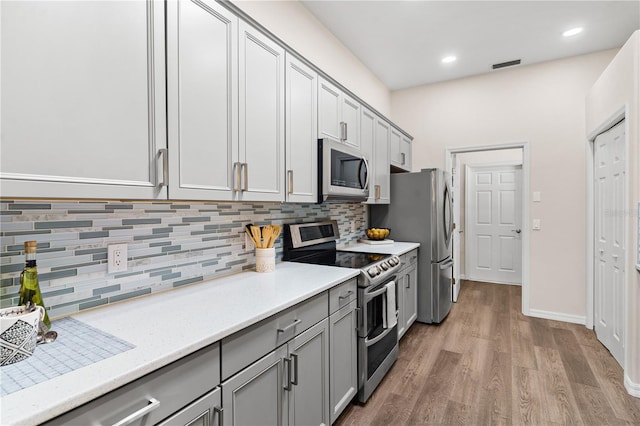 6152 Topsail Rd, Lady Lake, FL 32159 - kitchen with gray cabinets, stainless steel appliances, decorative backsplash, light wood-style floors, and visible vents