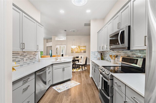 6152 Topsail Rd, Lady Lake, FL 32159 - kitchen featuring light countertops, stainless steel appliances, a sink, light wood-style flooring, and a peninsula