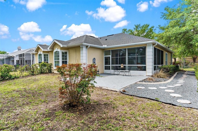6152 Topsail Rd, Lady Lake, FL 32159 - rear view of house featuring a patio area, roof with shingles, stucco siding, a sunroom, and a lawn