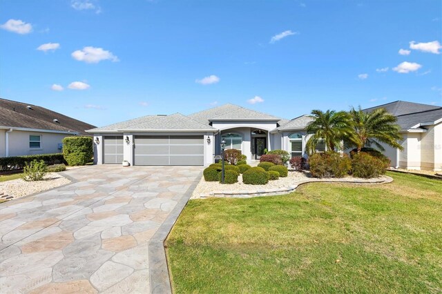 view of front of house with driveway, an attached garage, a shingled roof, stucco siding, and a front lawn