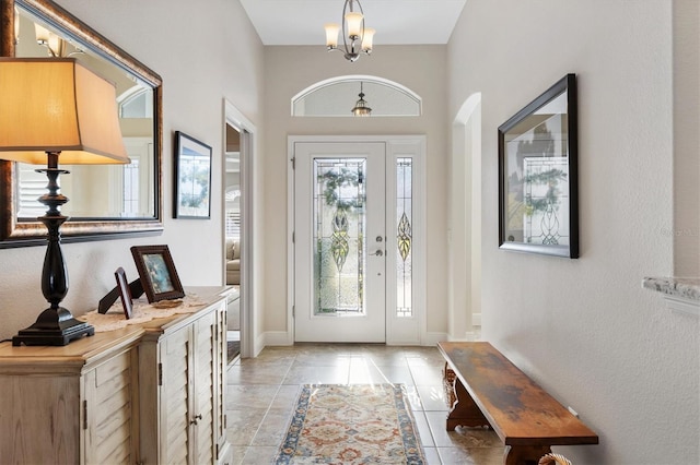 foyer entrance featuring a chandelier, baseboards, and light tile patterned flooring