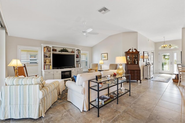 living room featuring vaulted ceiling, ceiling fan with notable chandelier, visible vents, and baseboards