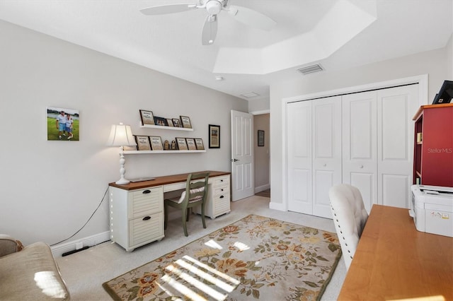 office area with visible vents, baseboards, light carpet, a raised ceiling, and a ceiling fan