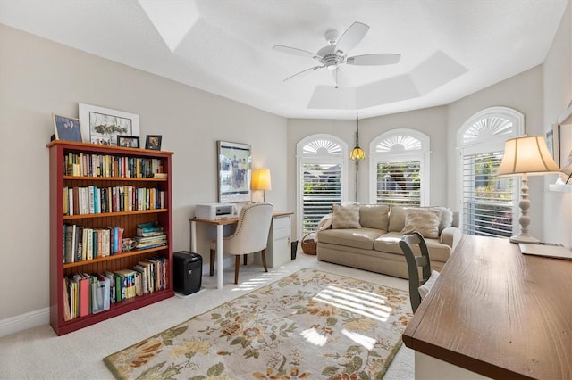 office area featuring a tray ceiling, baseboards, carpet floors, and ceiling fan
