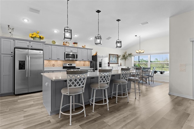 6444 Mcknight Loop, The Villages, FL 34762 - kitchen featuring appliances with stainless steel finishes, an island with sink, light wood-type flooring, a breakfast bar area, and tasteful backsplash