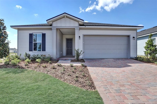 ranch-style home featuring board and batten siding, a front lawn, decorative driveway, and a garage