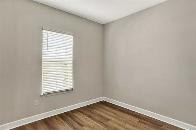 unfurnished room with baseboards and dark wood-style flooring