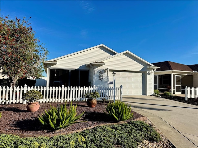 ranch-style house featuring driveway, a sunroom, a garage, and a fenced front yard