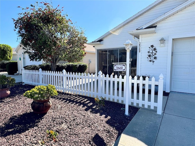 exterior space featuring a fenced front yard, an attached garage, and a sunroom