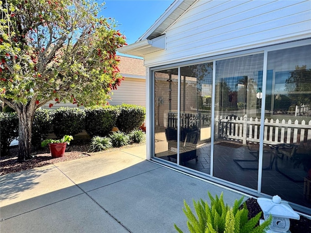 view of patio with fence and a sunroom