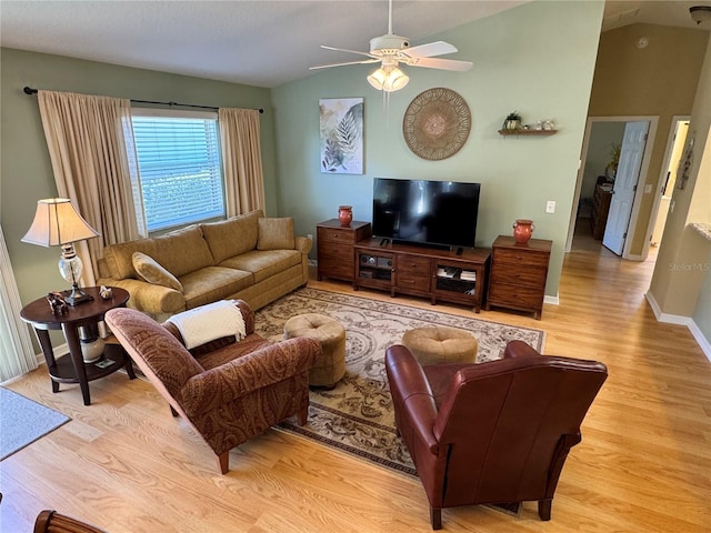 living area with baseboards, light wood-type flooring, ceiling fan, and vaulted ceiling
