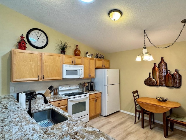 kitchen with a notable chandelier, a sink, white appliances, light wood-style floors, and vaulted ceiling