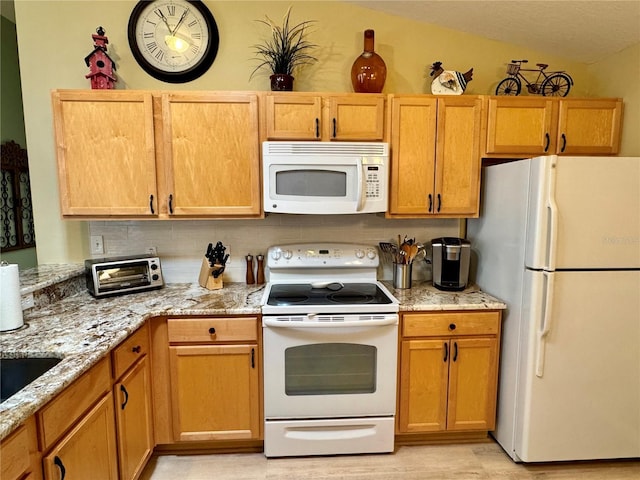 kitchen featuring white appliances, light stone counters, and a toaster