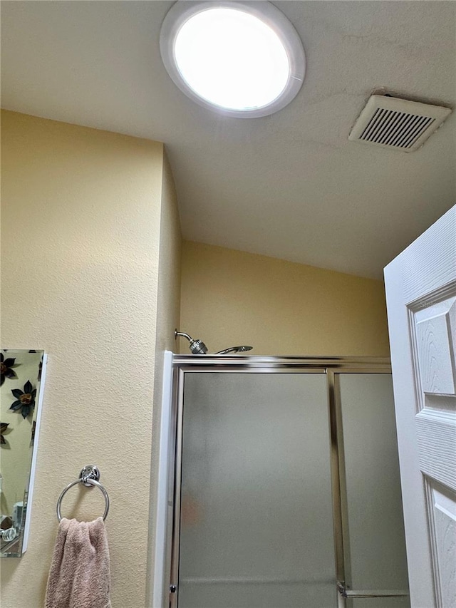 bathroom featuring visible vents, a stall shower, and a textured wall