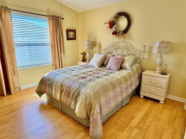 bedroom with light wood-style flooring, baseboards, and vaulted ceiling