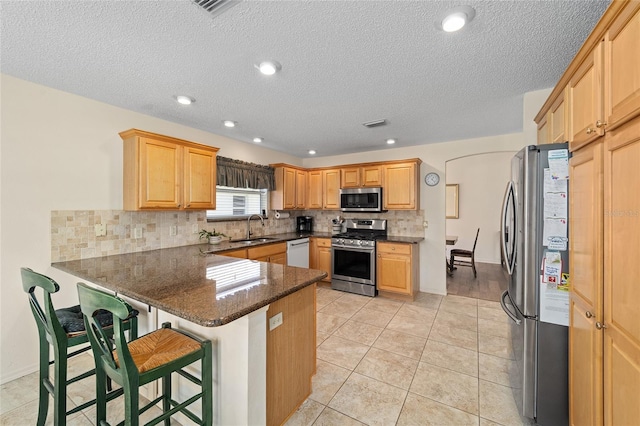 1417 Forest Acres Dr, The Villages, FL 32162 - kitchen featuring tasteful backsplash, dark stone countertops, appliances with stainless steel finishes, a peninsula, and a sink