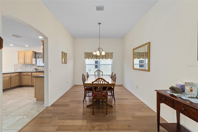 1417 Forest Acres Dr, The Villages, FL 32162 - dining space featuring visible vents, a chandelier, light wood-style floors, arched walkways, and a textured ceiling